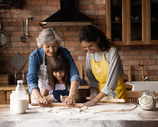 Familia multigeneracional preparando masa para tartas.