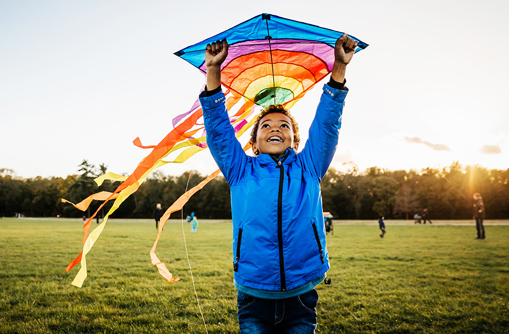 Boy in blue jacket launching kite