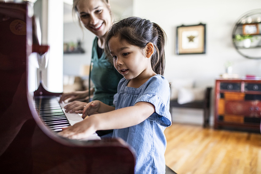 Niño tocando el piano con instructor