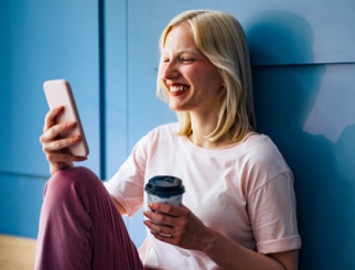 Woman holding cellphone and coffee