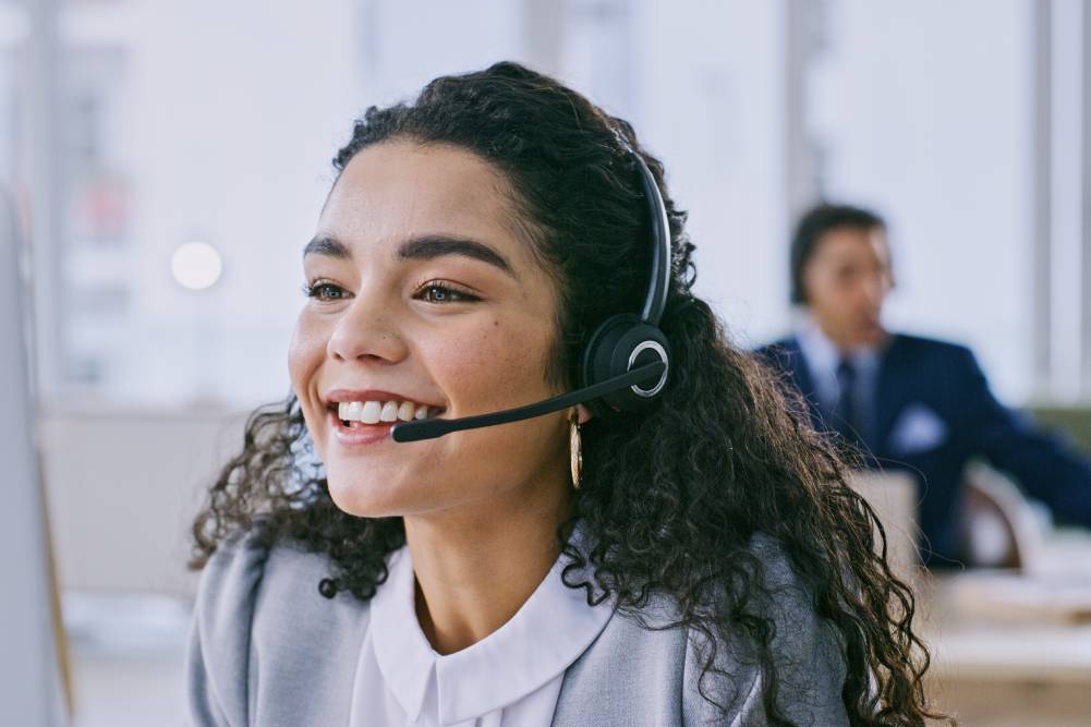 En la página 2024. Un representante de Servicio al Cliente sonríe mientras habla a través de sus auriculares.