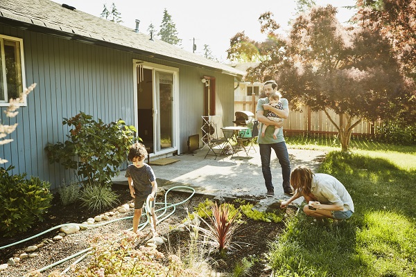 Family watering the garden in a sunny backyard