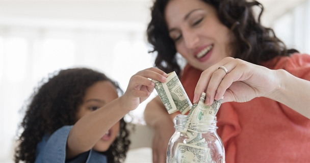 Madre e hija ponen dinero en un frasco.