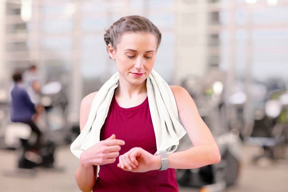 Mujer mirando su smartwatch en el gimnasio mientras gana recompensas Well OnTarget.