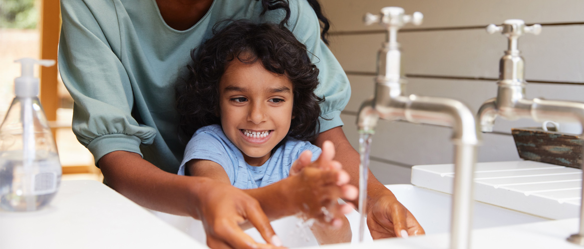 Woman helps child with handwashing