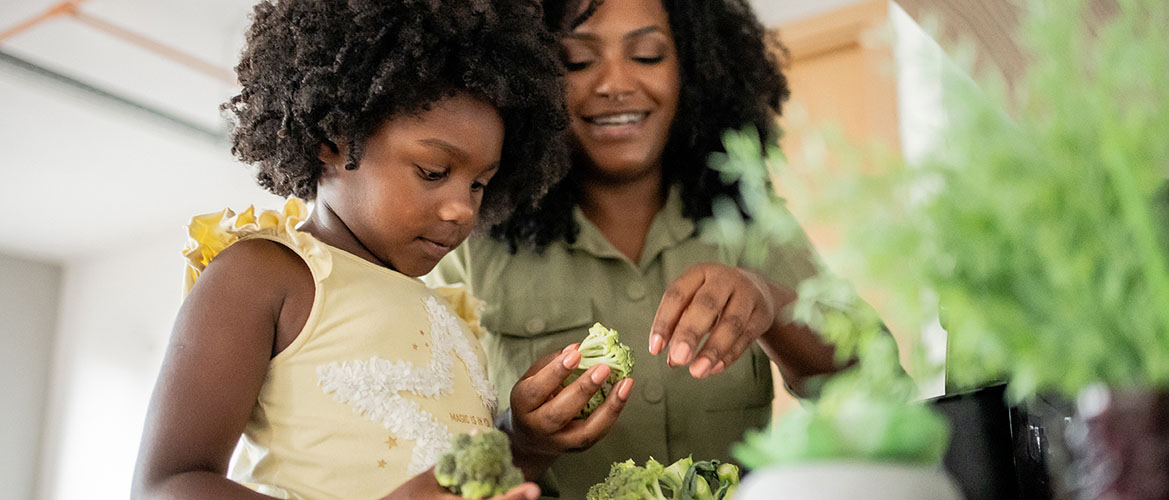 An African American woman and daughter prepare vegetables in a kitchen